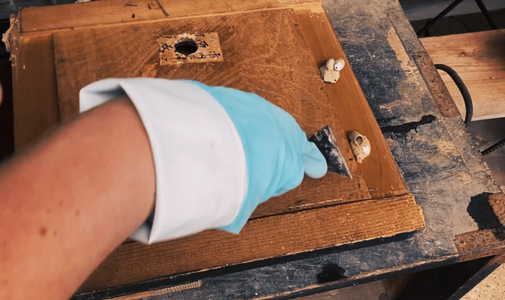 Scraping insect nests from the old tansu furniture door interior